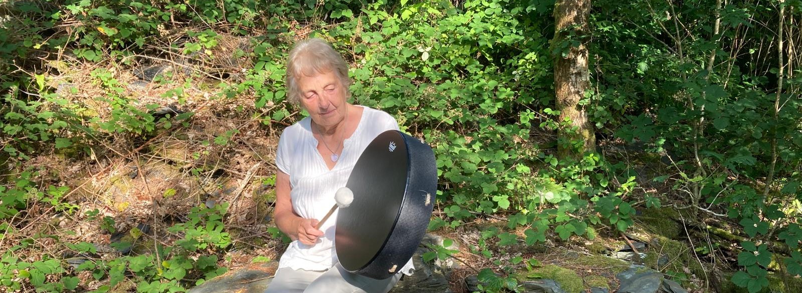 Maggie playing a drum in nature.